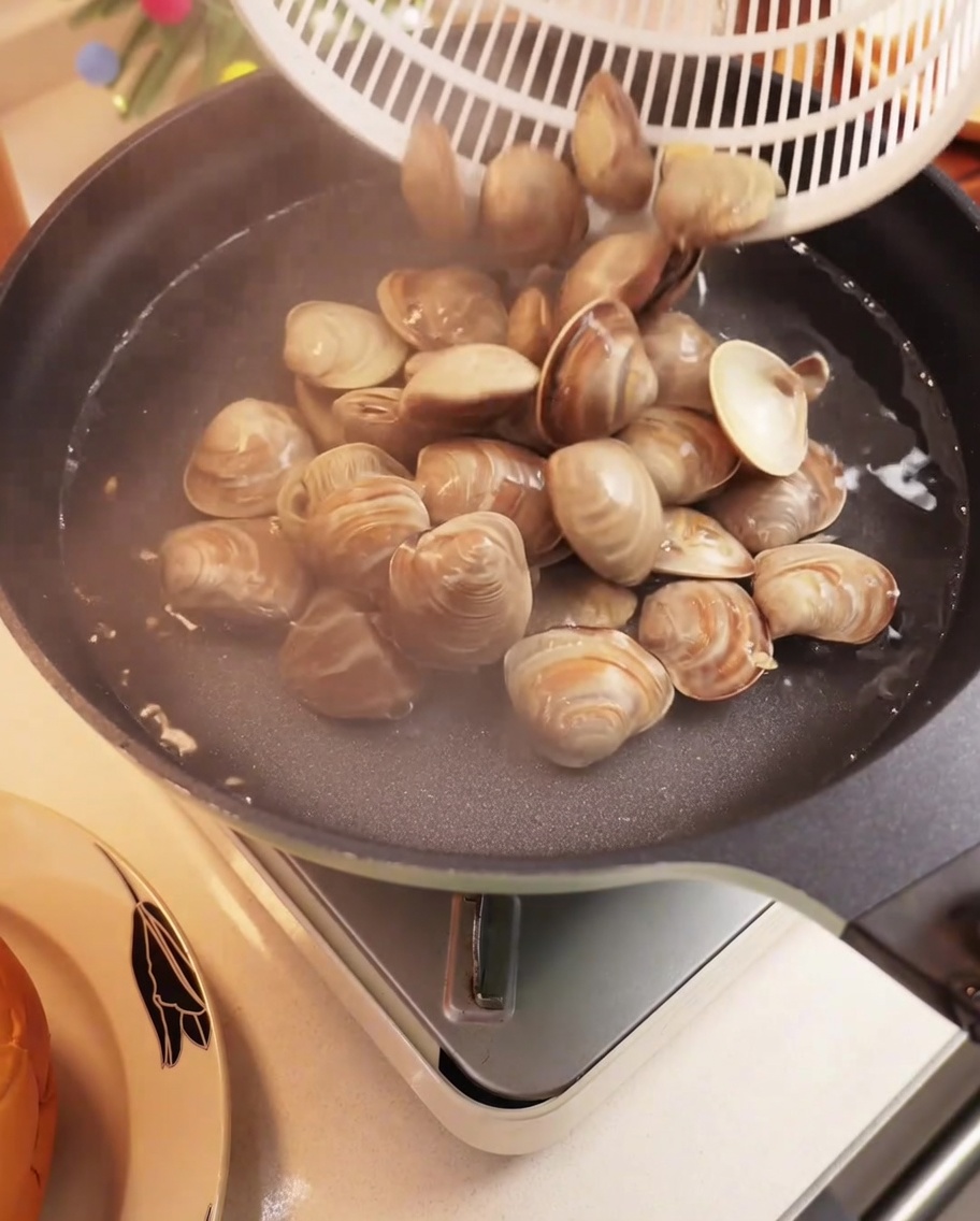 鍋で殻付きアサリを茹でている様子。