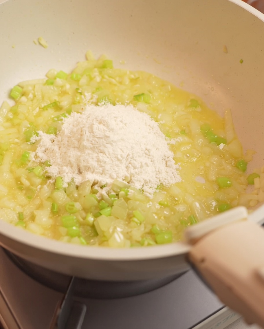 炒めた野菜に小麦粉を加え、混ぜ合わせている様子。