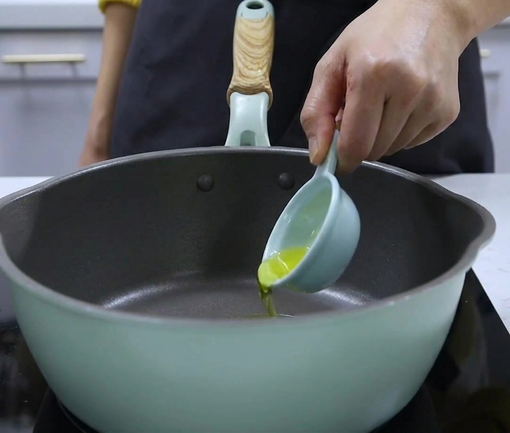 小さな計量スプーンから鍋にクルミ油を注いでいるところ。