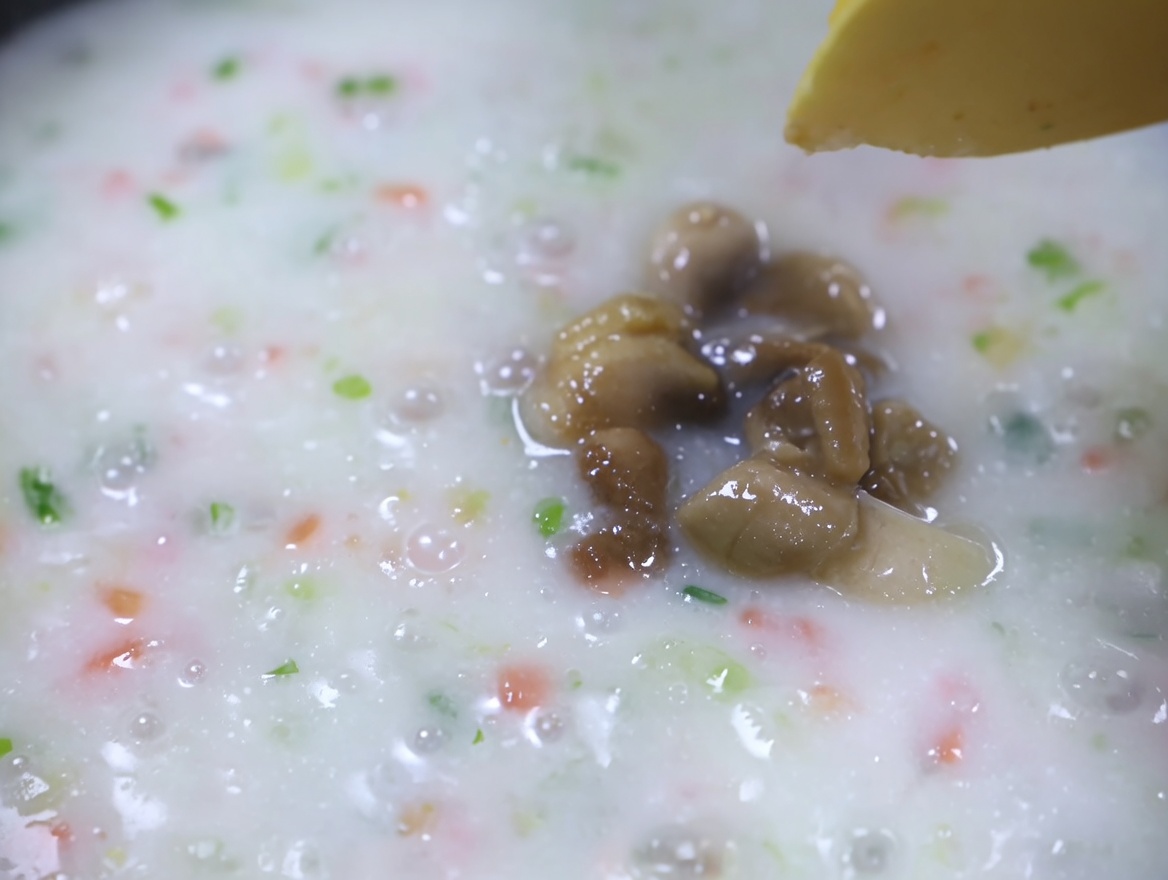 グツグツ煮立つクリーミーな野菜スープに、火を通したアサリの身を加えているところ。