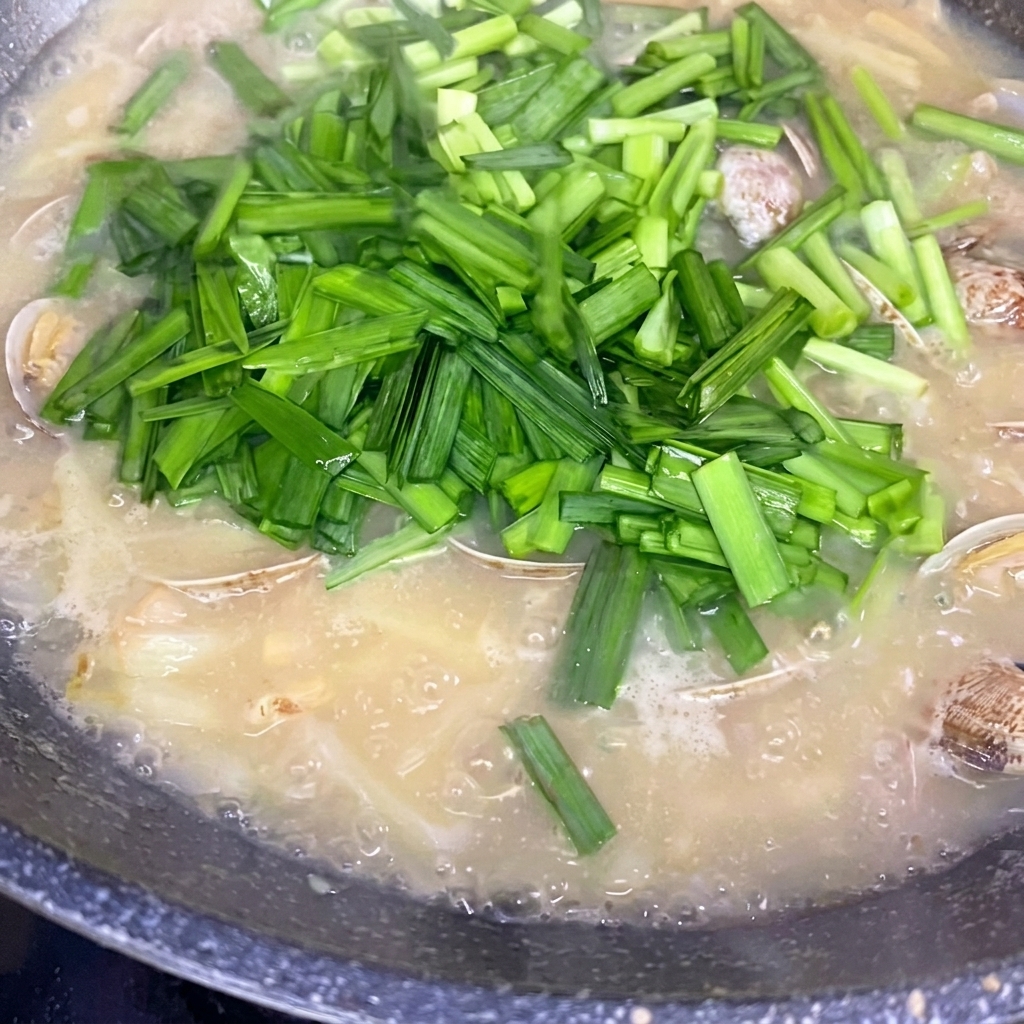煮上がったスープにニラを振りかけている様子。