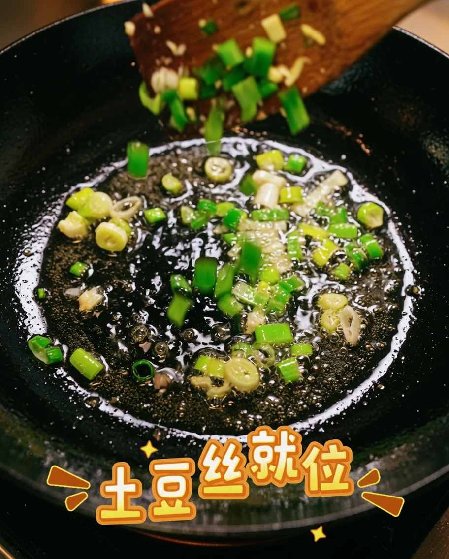 フライパンの中で千切りじゃがいもと炒めた青ねぎを混ぜ合わせている様子。