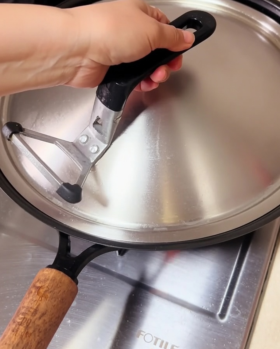 蓋をした中華鍋で、隙間から湯気を出しながらあさりを調理している様子。