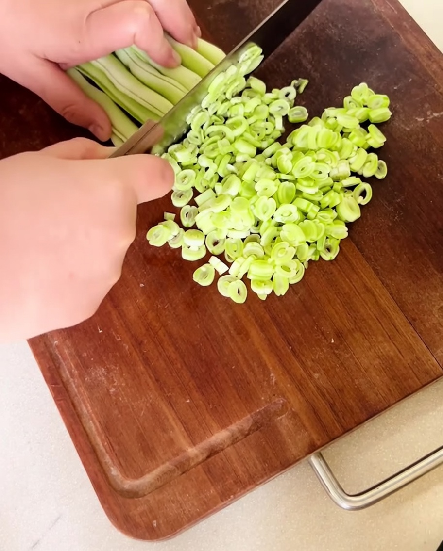 木製のまな板の上に広げられた、細かく刻まれた新鮮ないんげん豆。