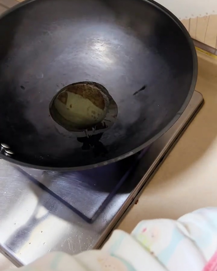 熱した中華鍋の油で、刻んだ青ねぎがジュージューと音を立てて炒められている様子。