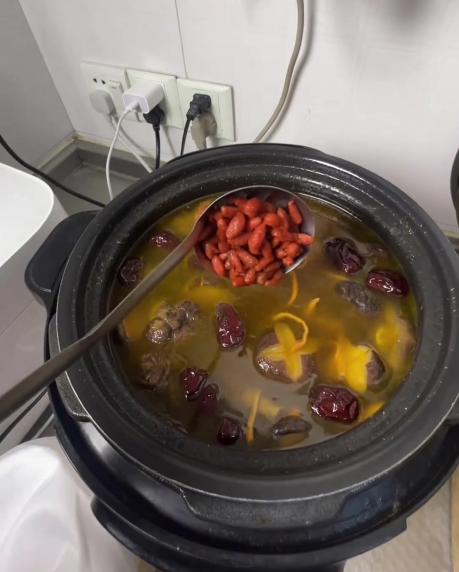 煮上がった鶏スープにクコの実を加えて仕上げている様子。