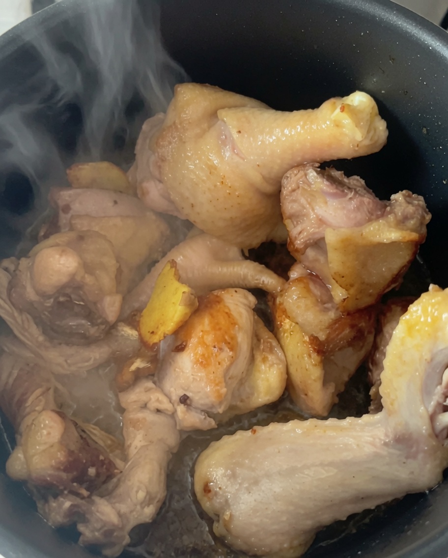 お湯を加えた圧力鍋の中の鶏肉から湯気が立ち上っている様子。