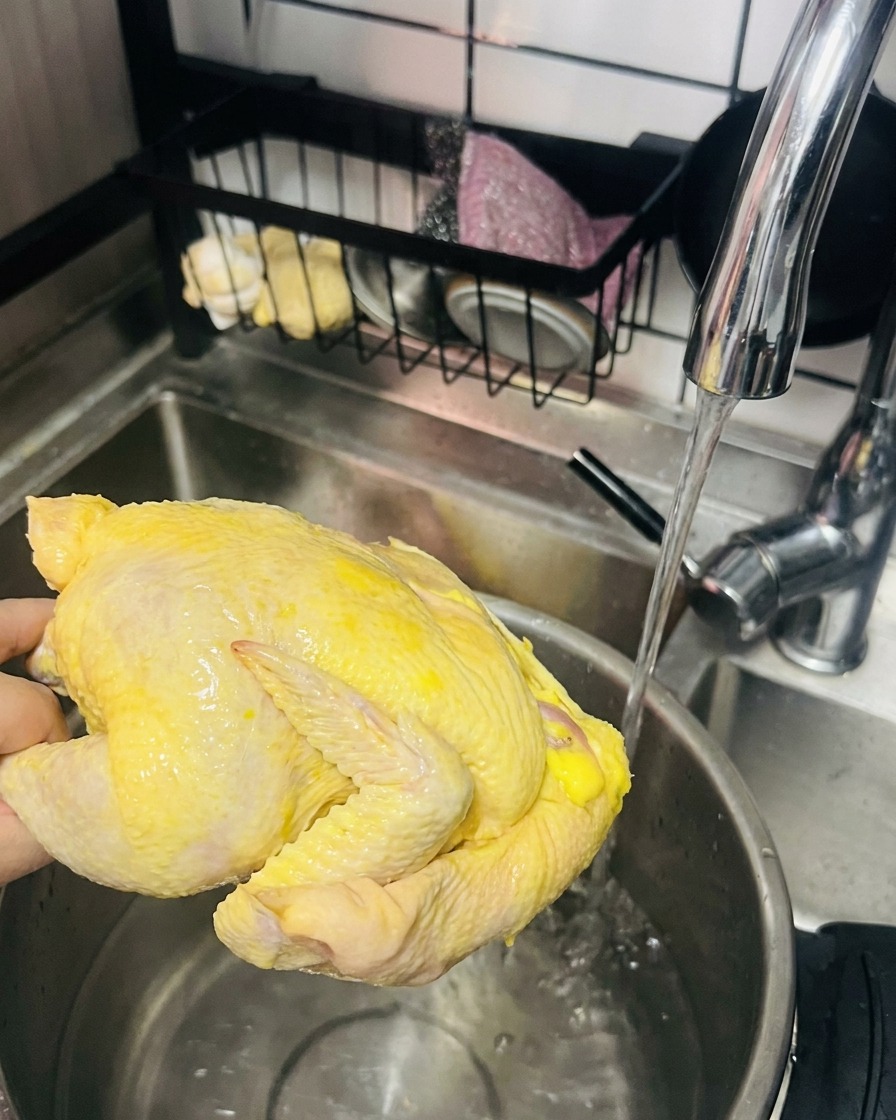 蛇口から出る水で親鶏を洗う手元の様子