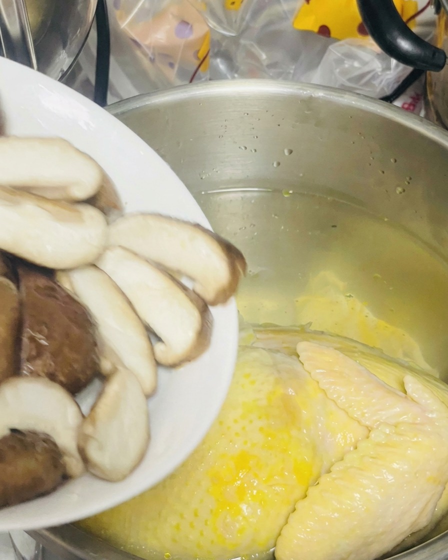 スライスした椎茸を鶏が入った鍋に加える様子