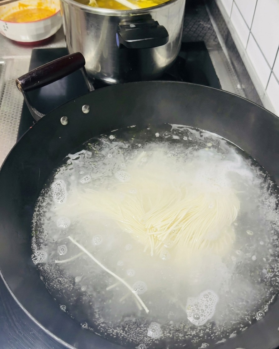 沸騰したお湯に細い麺を入れている様子