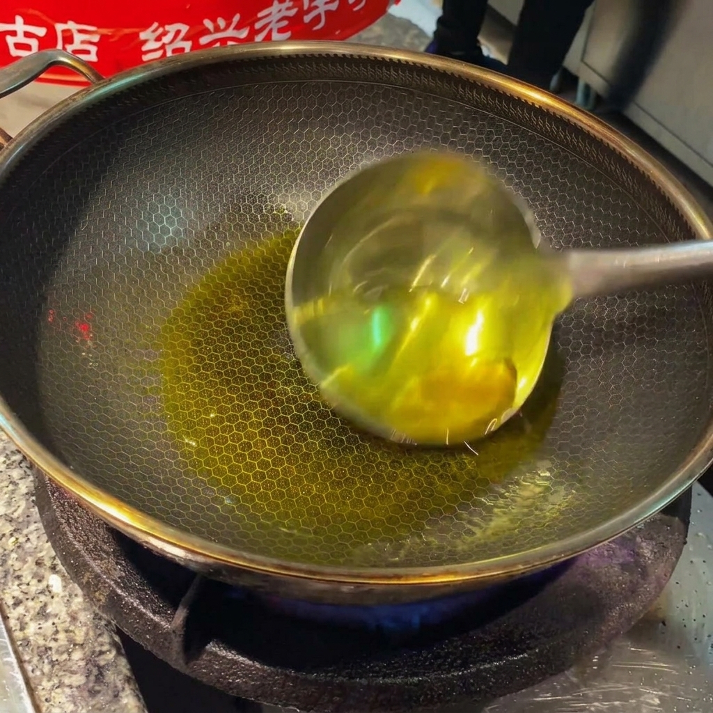 中華鍋の熱い油で炒められる薄切り生姜とにんにく。