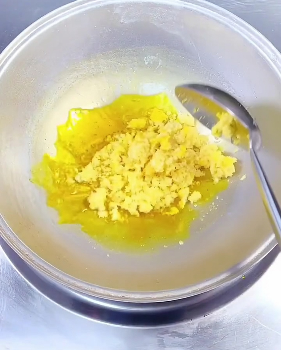 中華鍋の熱い菜種油の中で、みじん切りのにんにくを金属製のスプーンで混ぜている様子。