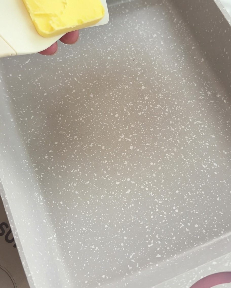 長方形のフライパンでバターの塊が溶けて液体状になっている様子。