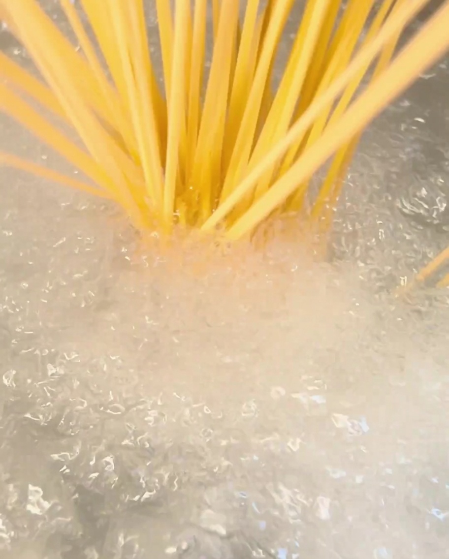 沸騰したお湯の入った鍋に乾燥スパゲッティを入れている様子。