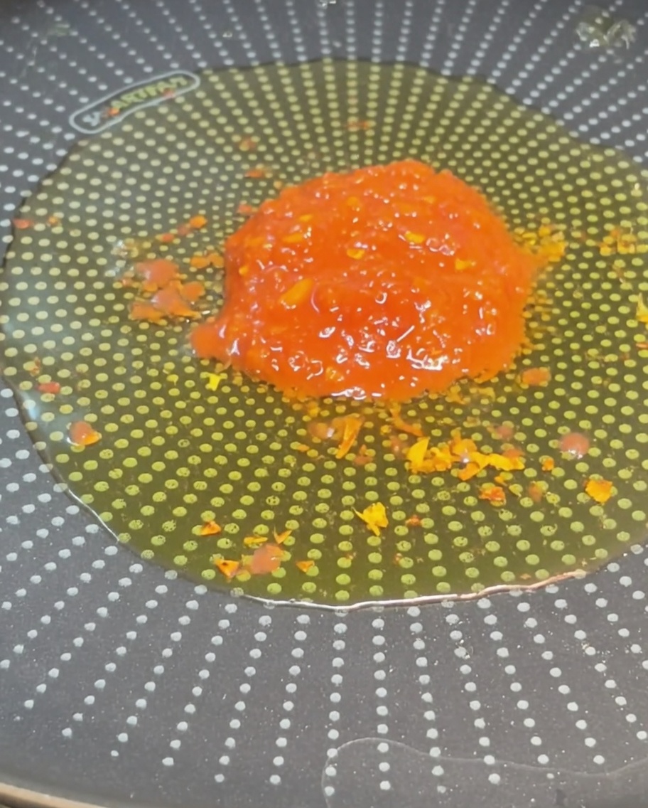 風味豊かなオリーブオイルが入ったフライパンの中央に、真っ赤なカットトマトを入れた様子。