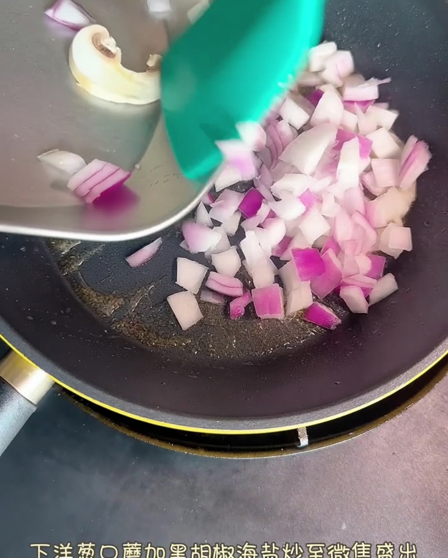 フライパンで赤玉ねぎとスライスしたキノコが炒められている様子