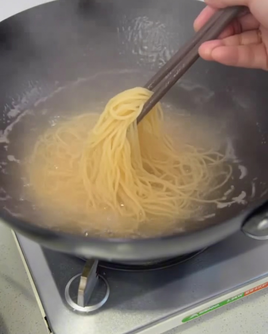 茹で上がったスパゲッティを菜箸で引き上げている様子。