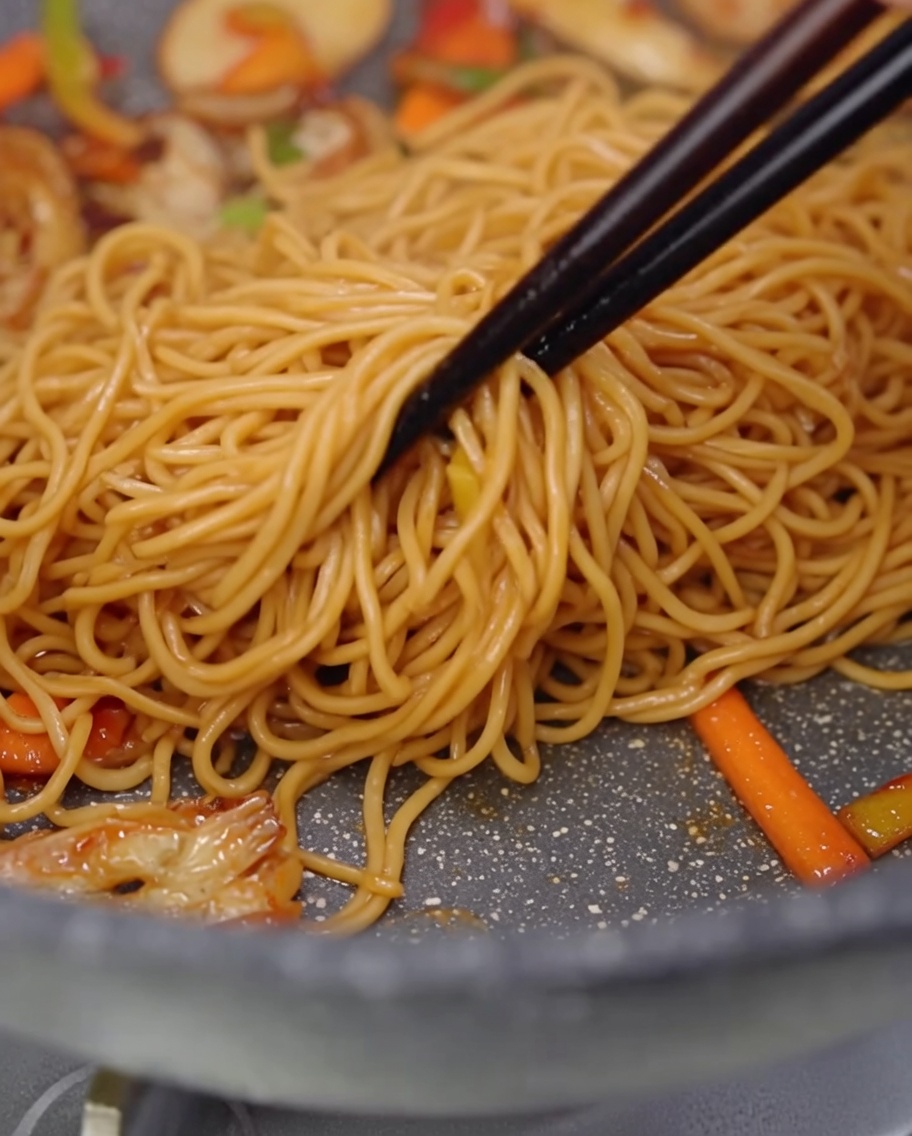 フライパンの中でパスタを混ぜ合わせている様子。