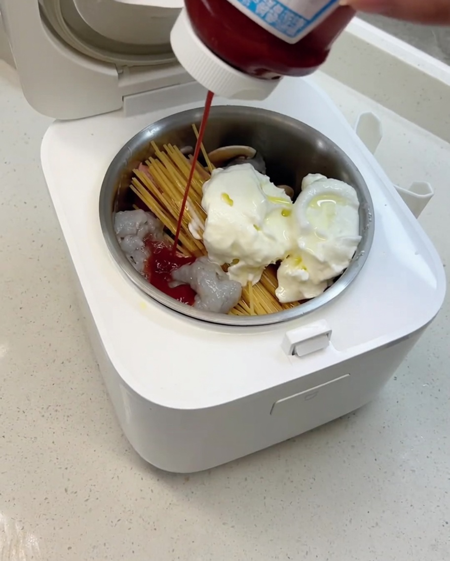 炊飯器にオリーブオイルとトマトソースを注いでいる様子。