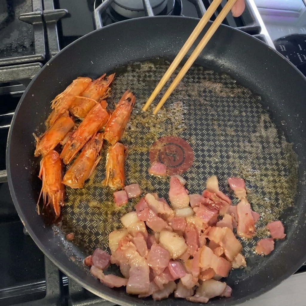 フライパンで海老を焼き、色が変わり始めている様子。