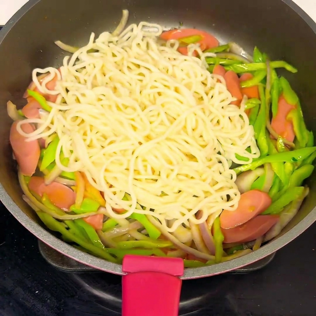 麺と具材にソースをかけて絡めている様子。