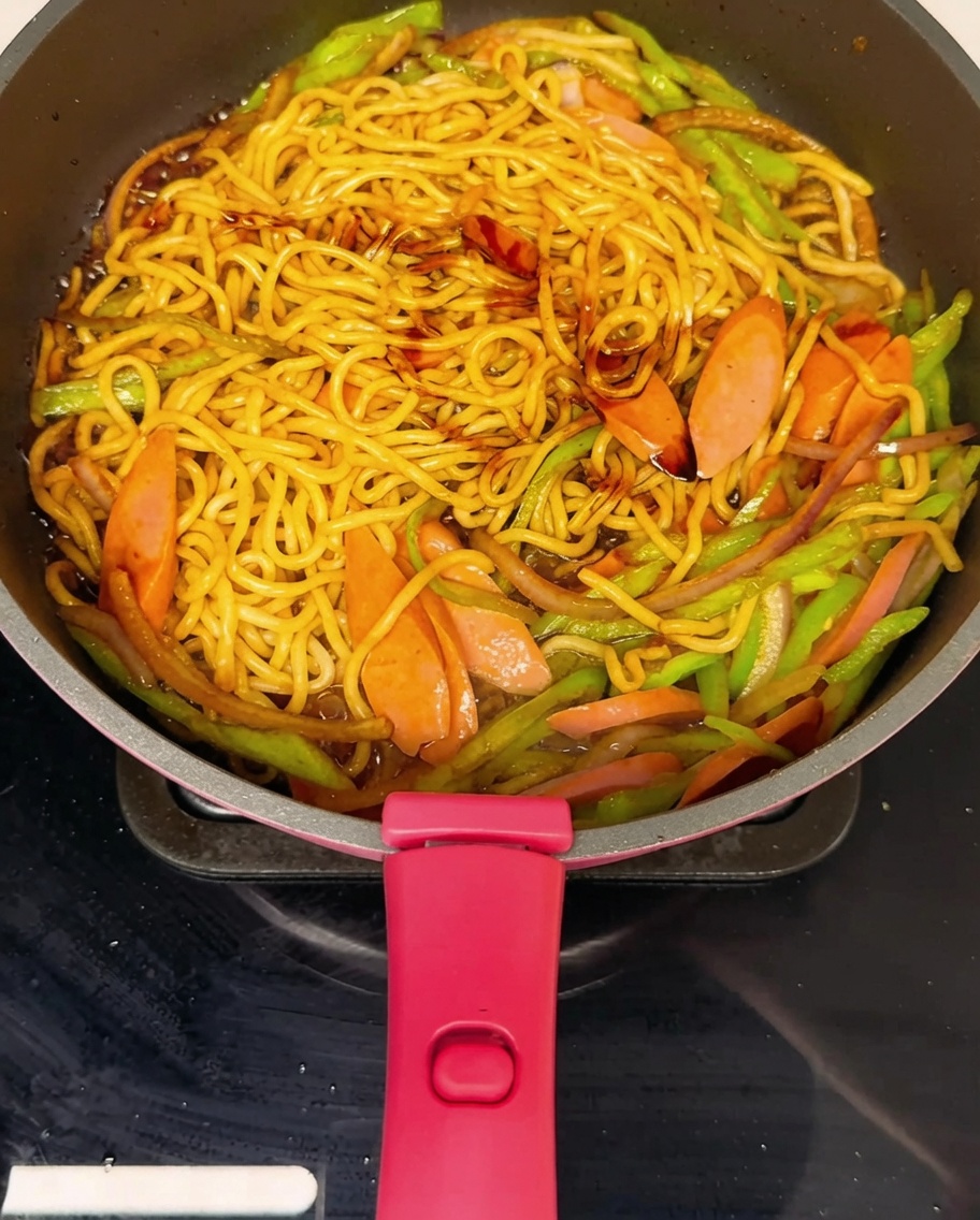 皿に盛る直前の焼きそばに黒胡椒を振っている様子。