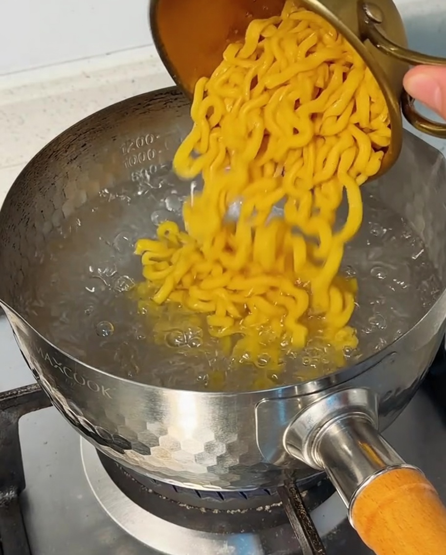 沸騰した鍋にマカロニを入れている様子。