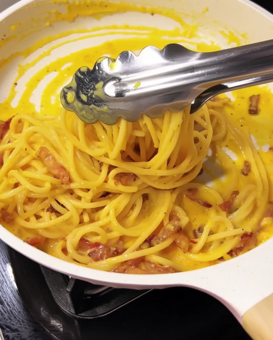 トングを使ってパスタを盛り付けている様子。