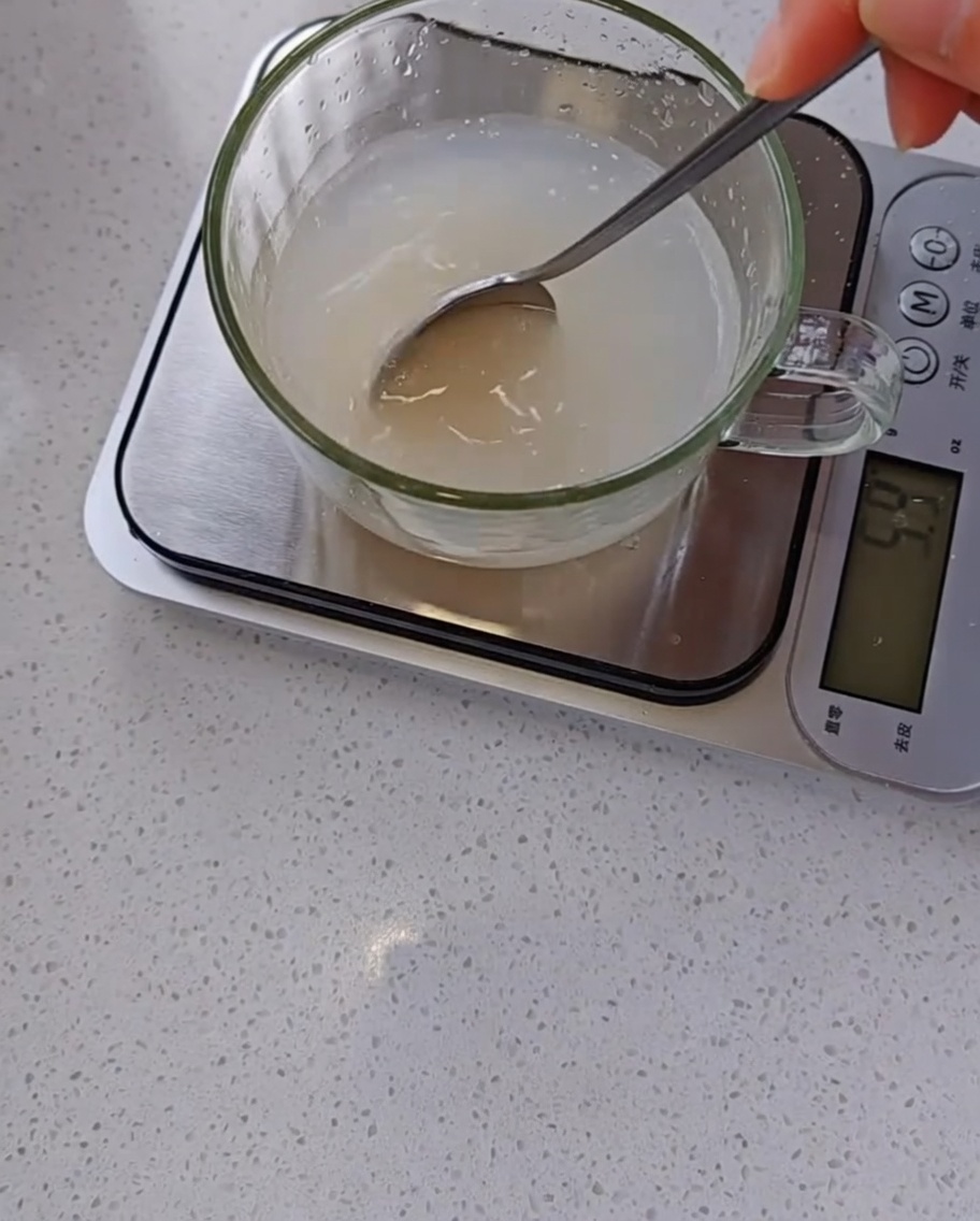 計量カップに入った水とイーストを、スプーンで混ぜ合わせている様子。