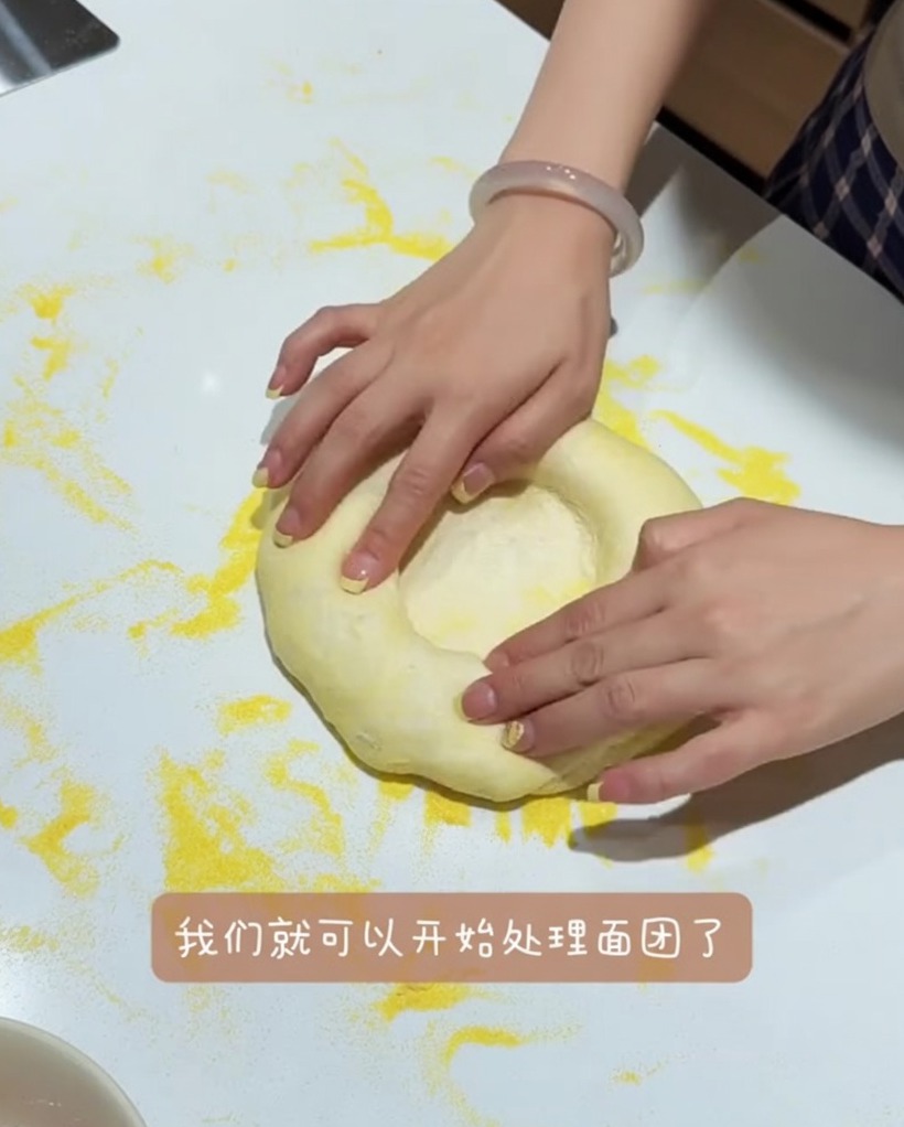 外側の縁を残しつつ、作業台の上で優しく伸ばされるピザ生地。