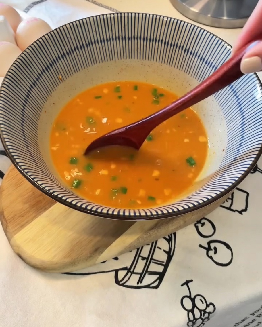 茹で上がった麺をトングでボウルのスープに入れる様子。