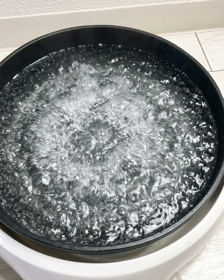 沸騰したお湯に卵をそっと入れている様子。