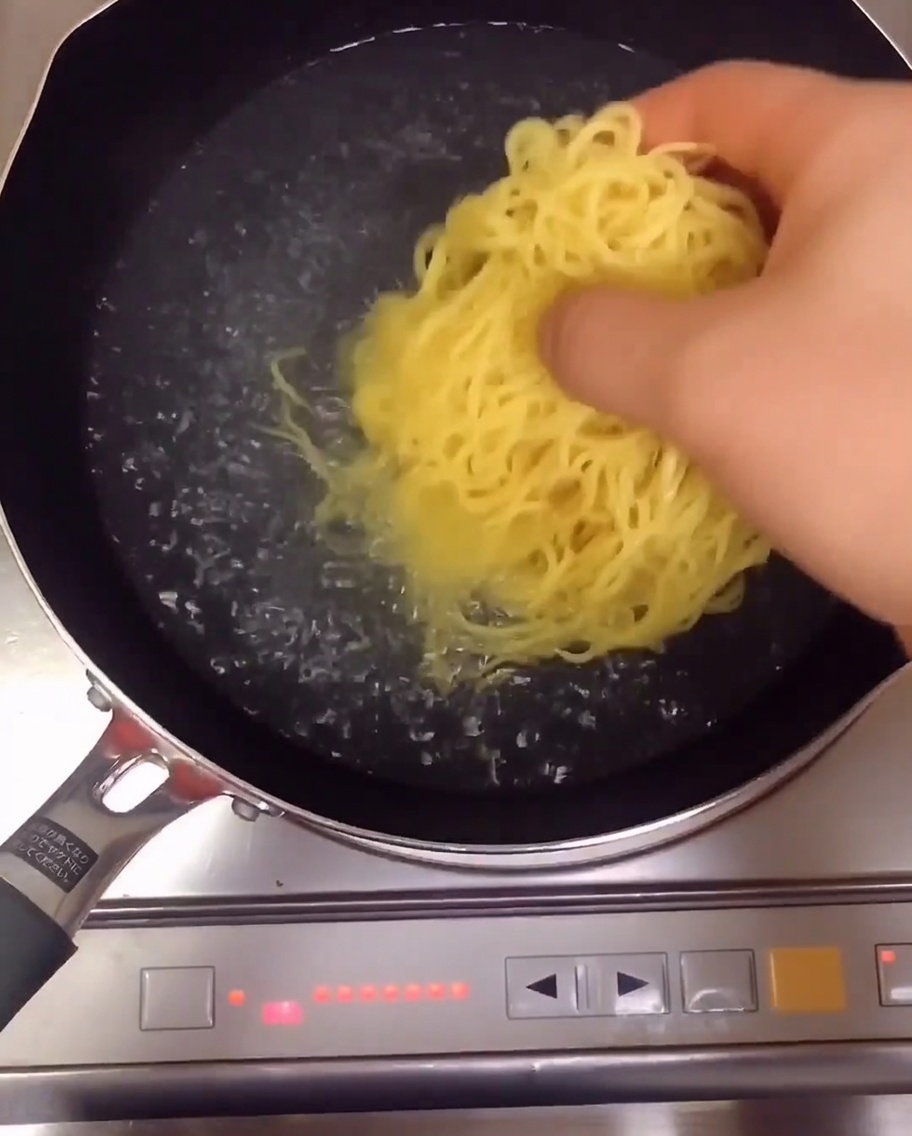 鍋の中でラーメンの麺が茹で上がっている様子。