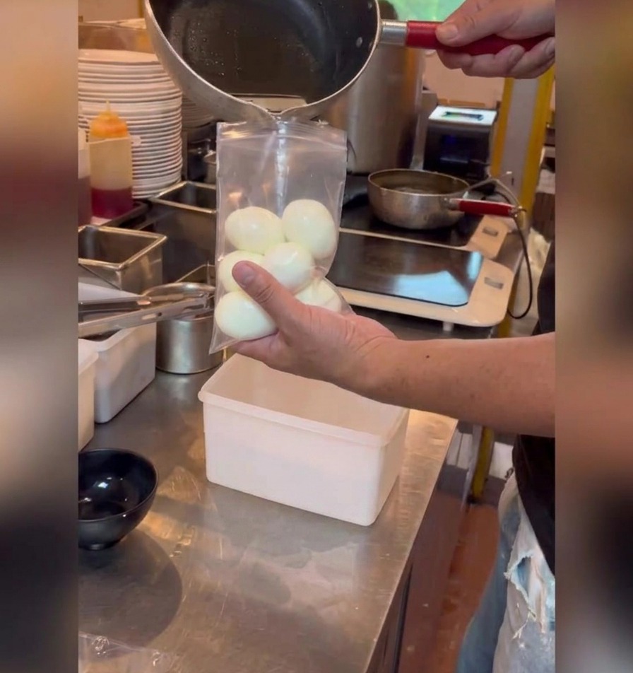 醤油ダレを、卵を入れた密閉袋に注ぎ込んでいる様子。