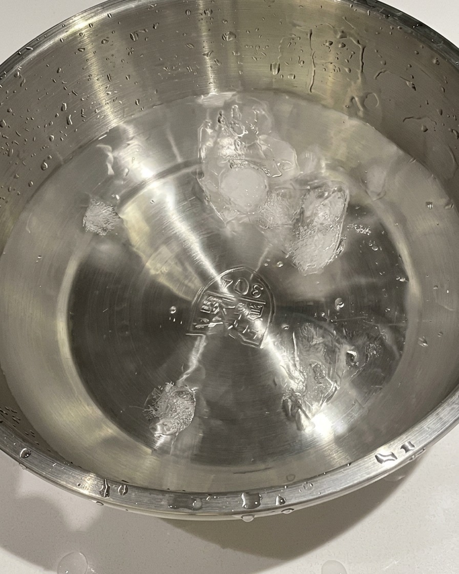 茹で上がった卵を鍋から氷水の入った金属製のボウルに移す様子。