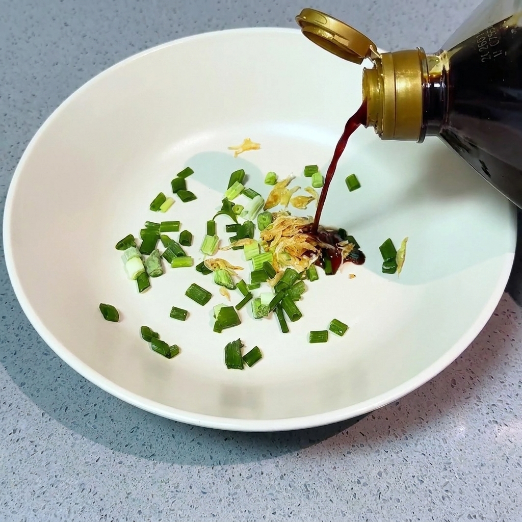 ねぎと乾燥海老が入った丼に、薄口醤油を注ぐ様子。
