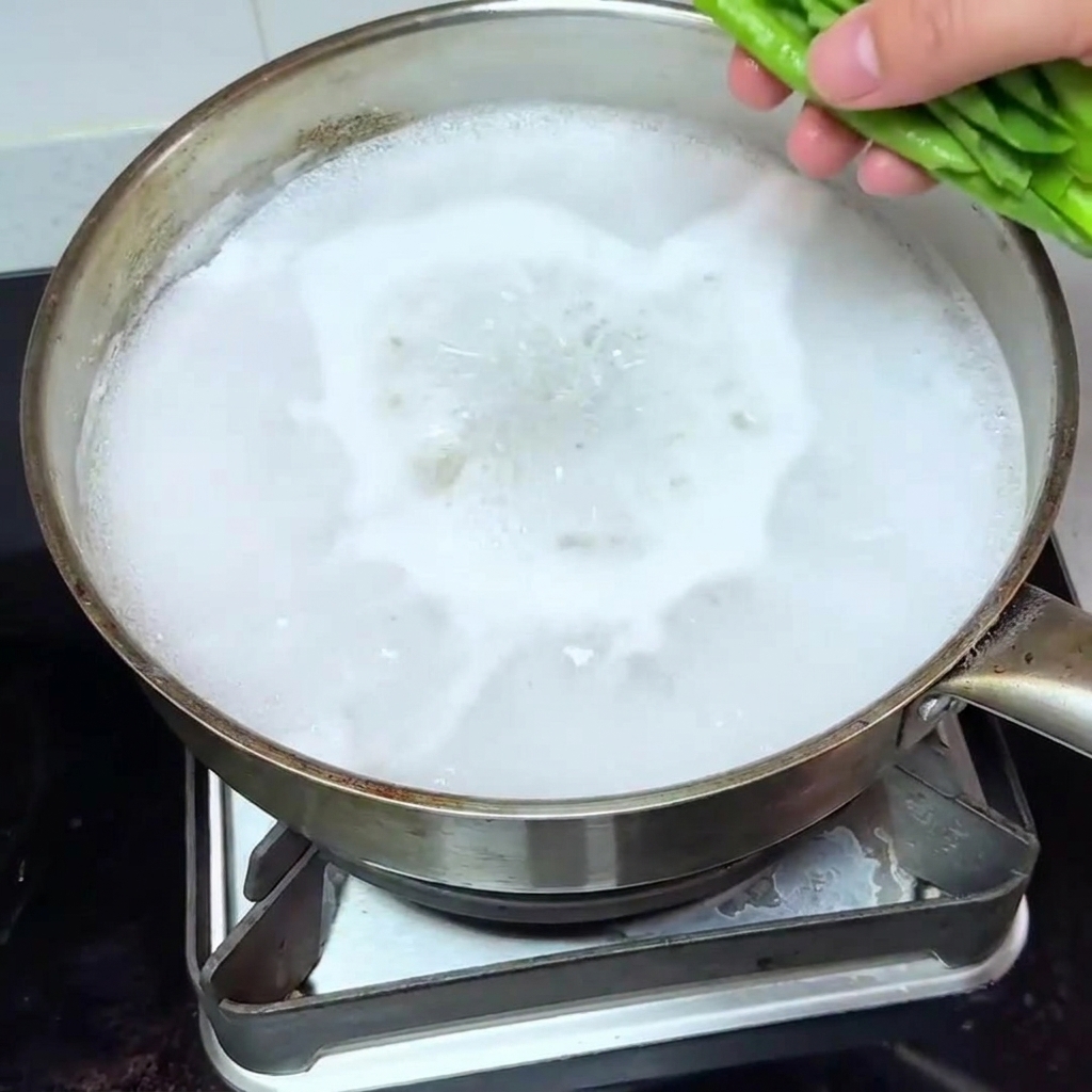 麺を茹でた後の鍋に青梗菜を加えて茹でる様子。