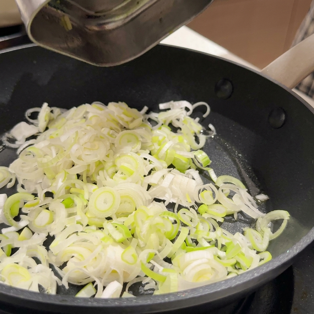 フライパンで油を熱し、ねぎとにんにくを炒めている様子。