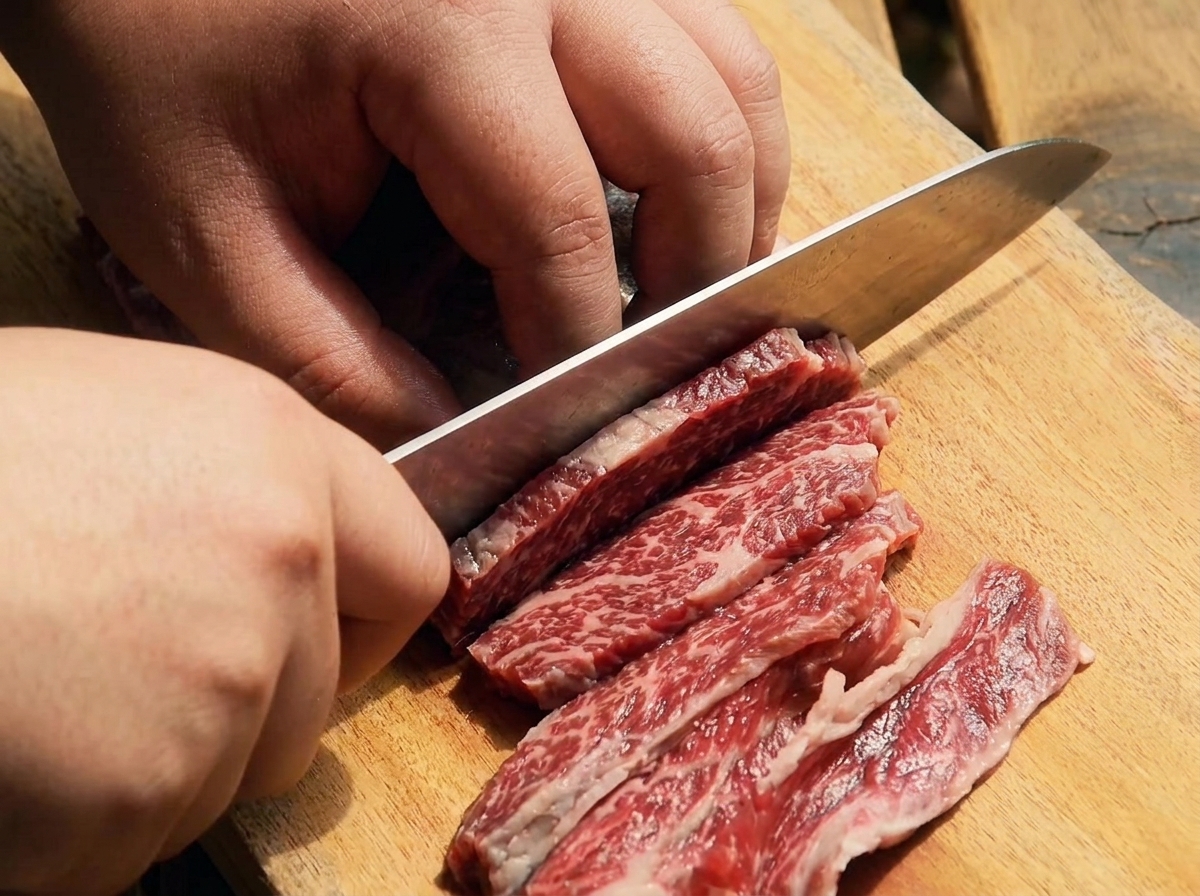 まな板の上で牛カルビを薄くスライスしている様子。