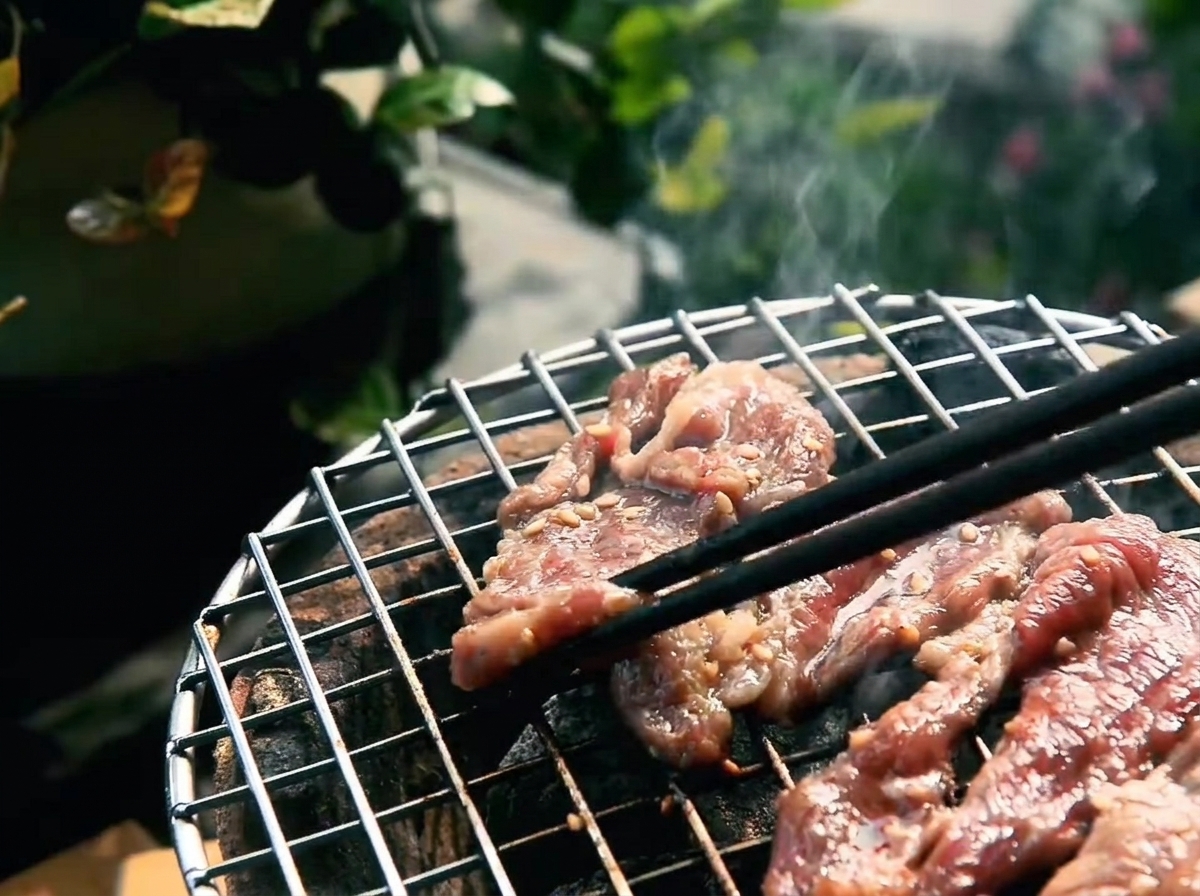 網の上で焦げ目がつき、脂がのって焼けている牛肉。