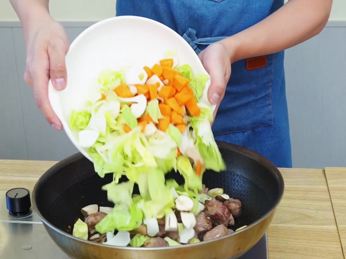 フライパンで牛肉と野菜を一緒に炒めている様子。