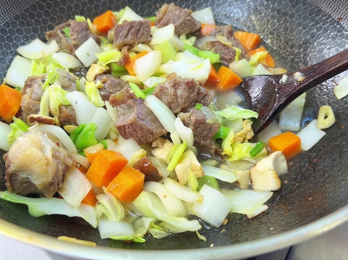 鍋の中の牛肉と野菜に水を加え、煮込んでいる様子。