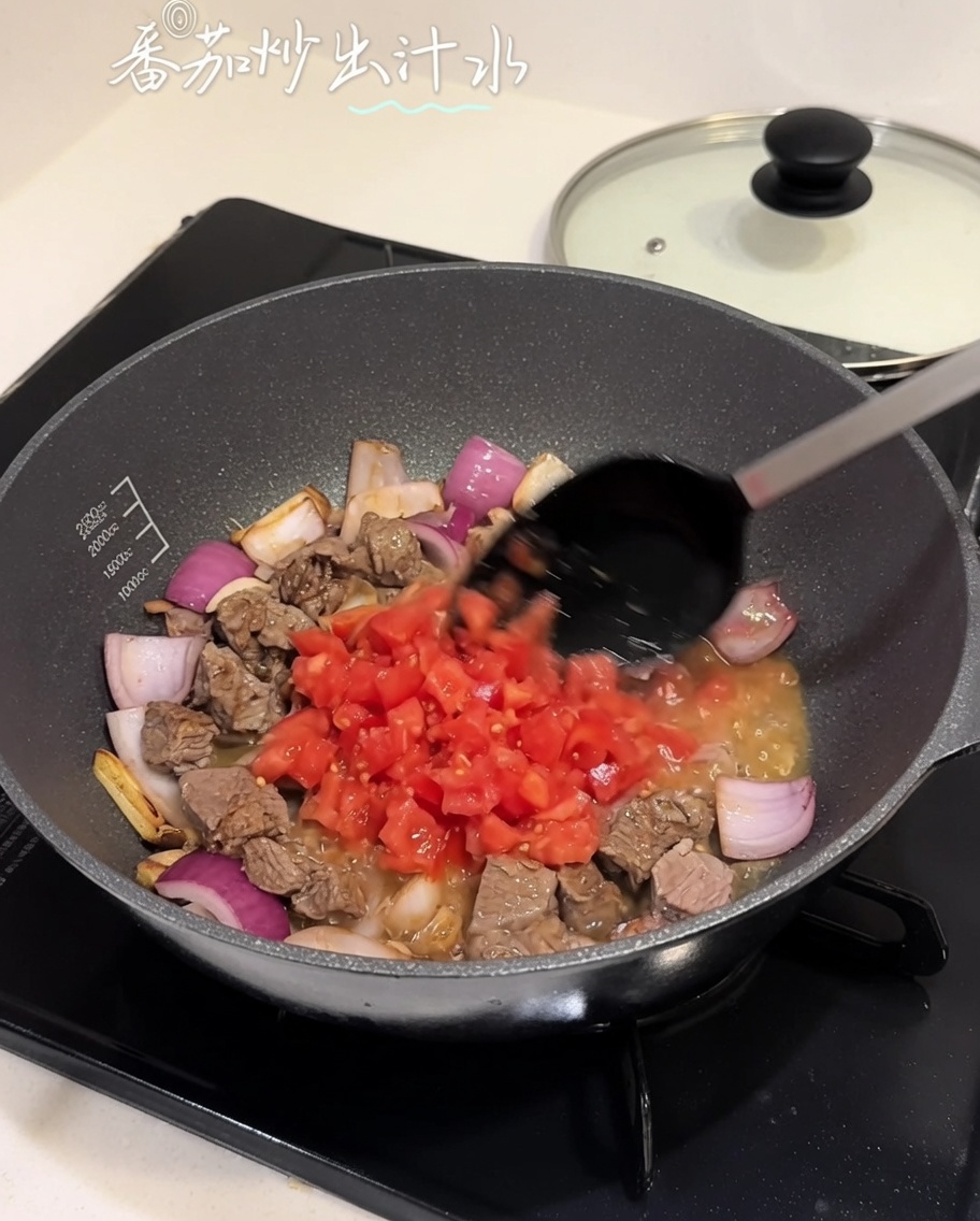 牛肉と玉ねぎの混合物に刻みトマトを加えている様子