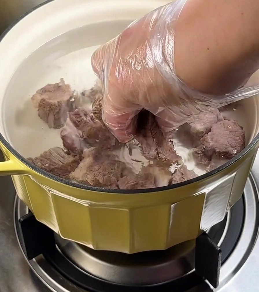 蓋をした鍋で牛バラ肉をコンロで煮込んでいる様子。