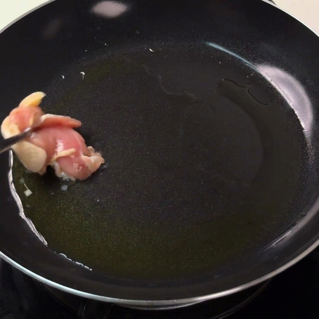 熱したフライパンに油をひき、鶏肉がきつね色になるまで焼いている様子。