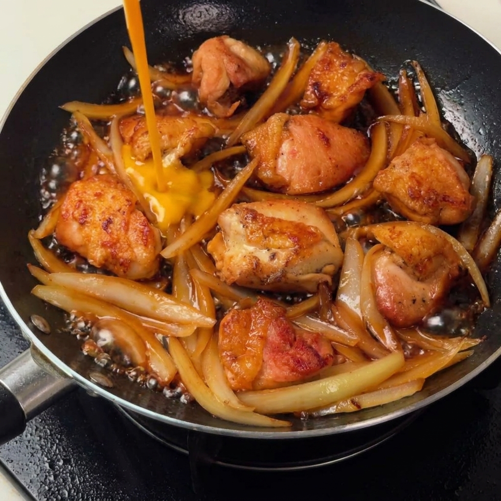 鶏肉と玉ねぎの上から溶き卵を回し入れ、ふんわりととじている様子。