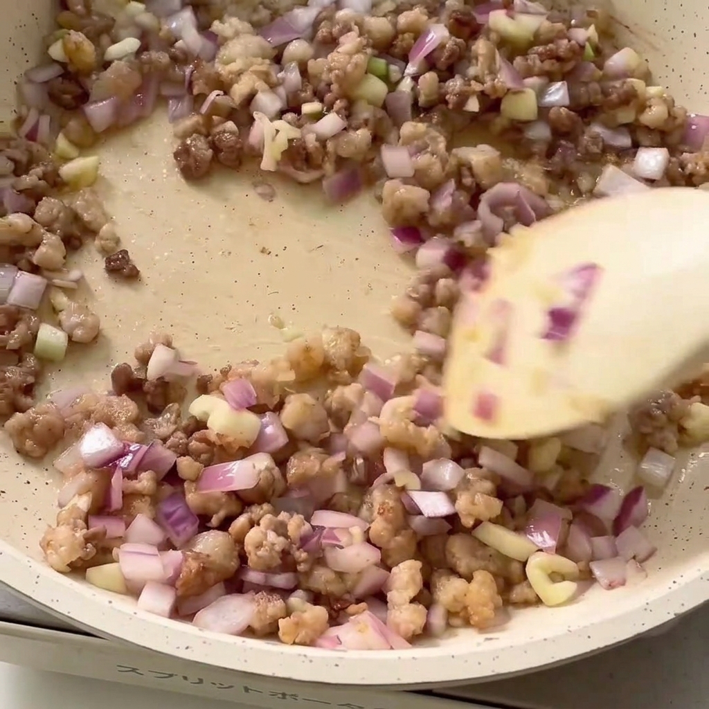 ひき肉と玉ねぎが入ったフライパンに調味料を加える様子。