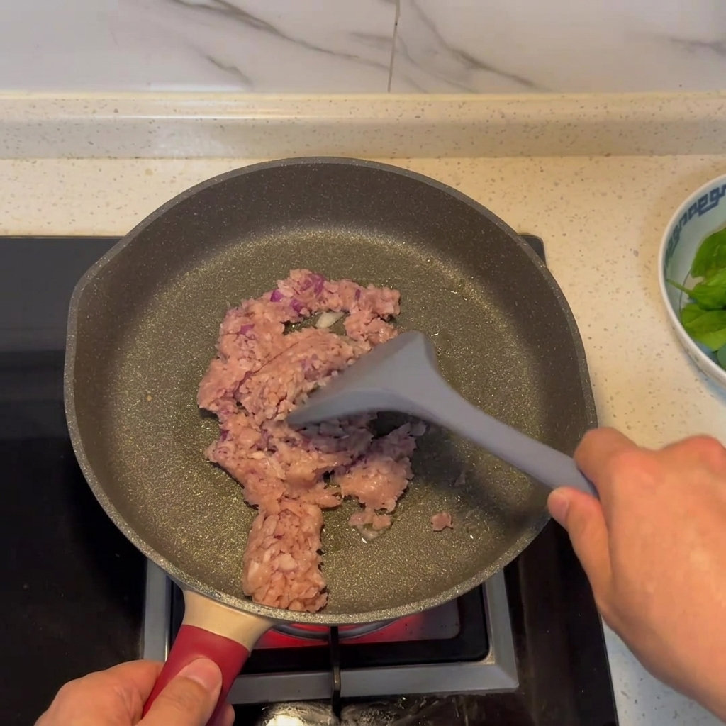 フライパンでひき肉と玉ねぎが炒められている様子。