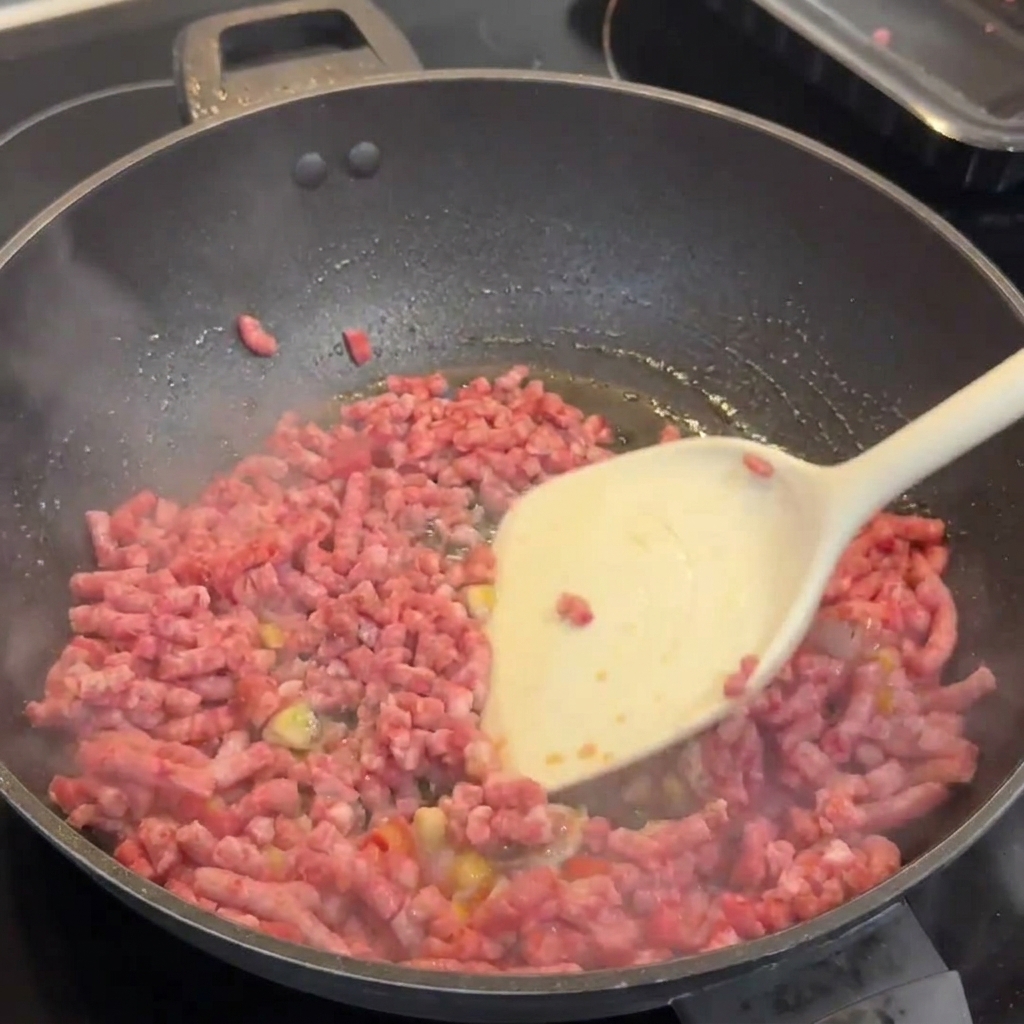 へらで肉をほぐしながら炒めている様子。