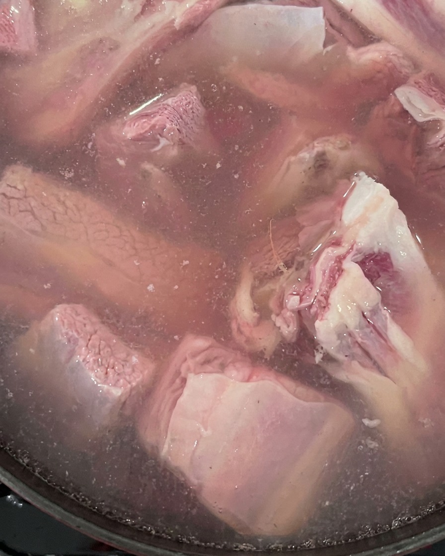 鍋の中で肉と生姜が水に入れられ、茹でられている様子。